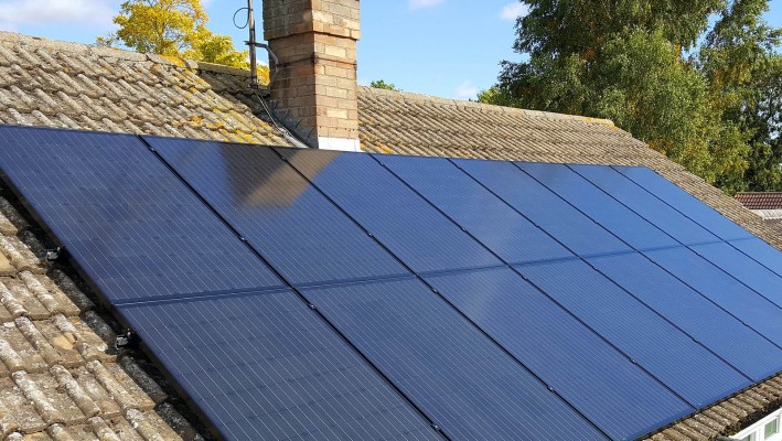 Sixteen solar panels on an open gable roof over a small bungalow in Cambridge