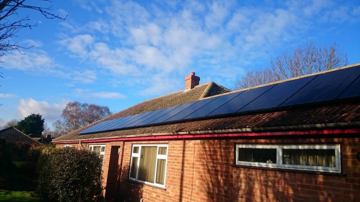 One long row of solar panels installed on top of a bungalow house near Cambridge