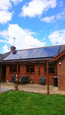 Medium bungalow house near Cambridge with two new rows of solar panels on a nice summer morning